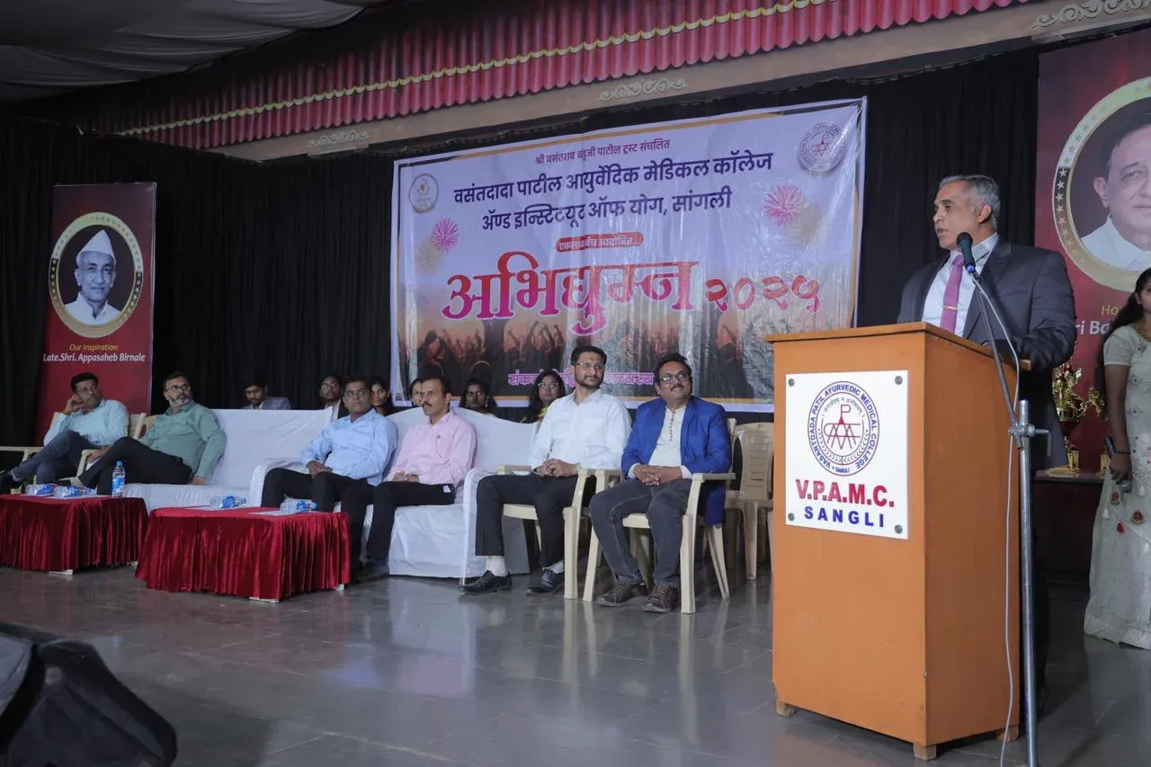 A speaker at a podium on stage with a seated panel behind