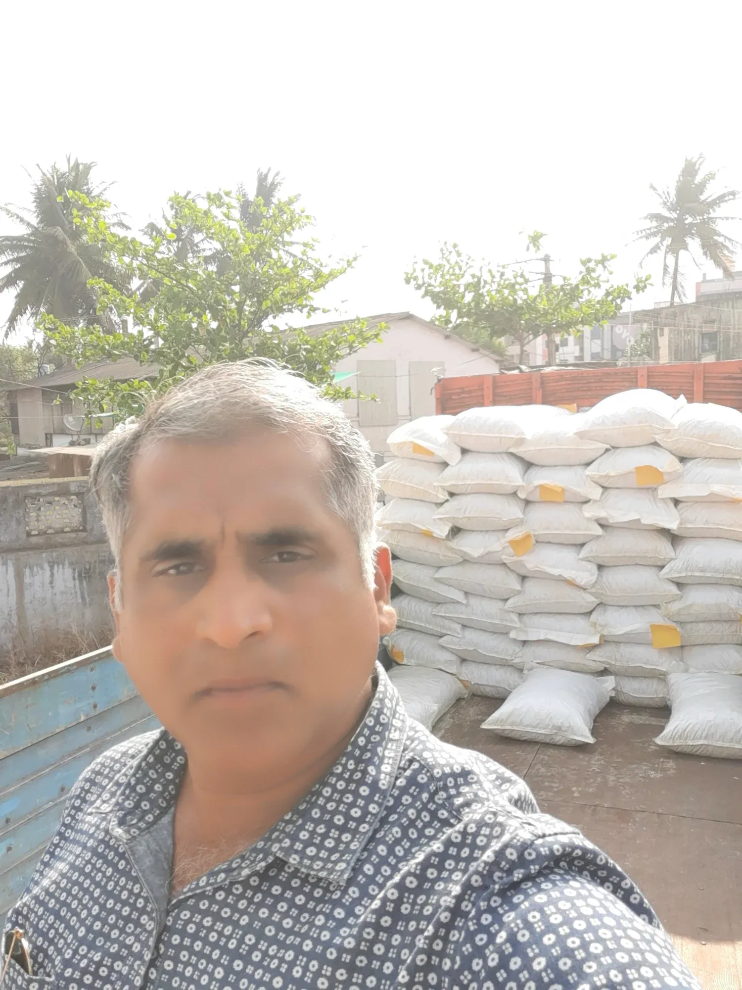 The procurement lead at the mill yard in front of stacked filled sacks