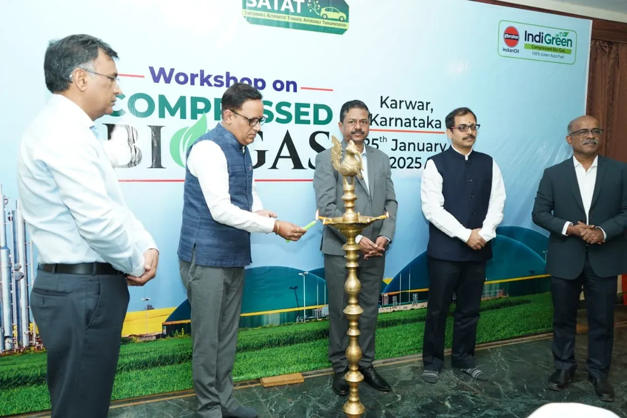 Four men standing beside a Compressed Biogas workshop banner at Karwar