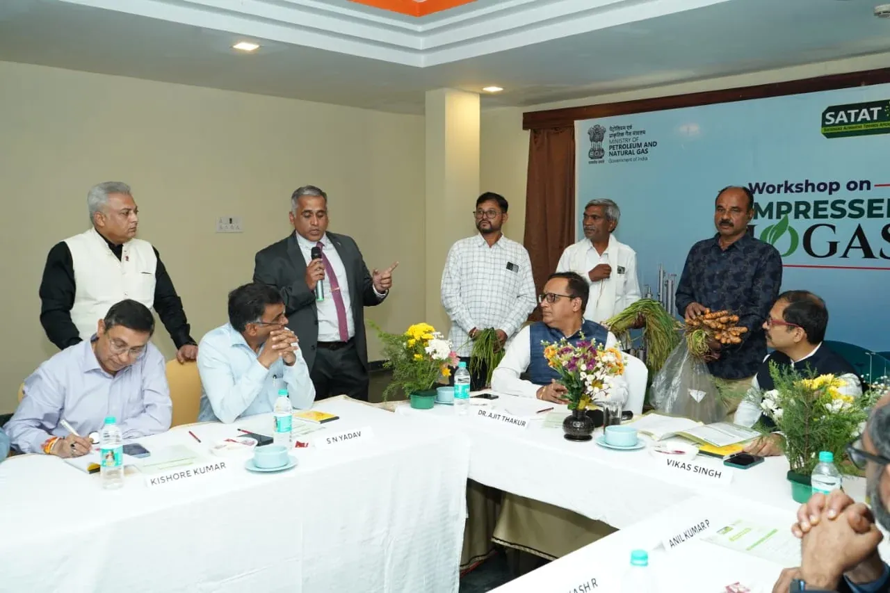 Officials seated at a named-place conference table beneath a SATAT Compressed Biogas workshop banner