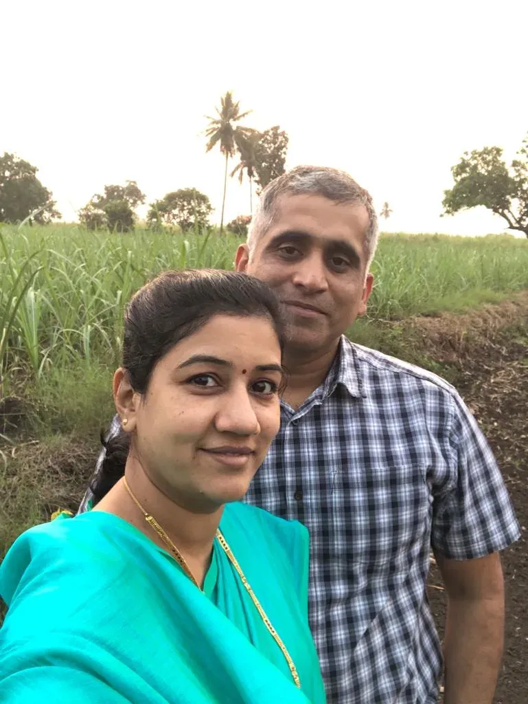 Mrs. Khochare and the Captain at the edge of a sugarcane field at dusk, palms on the horizon