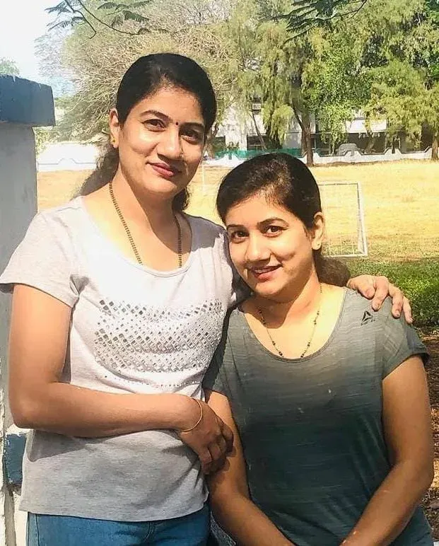 The twin sisters side by side outdoors, an arm around each other