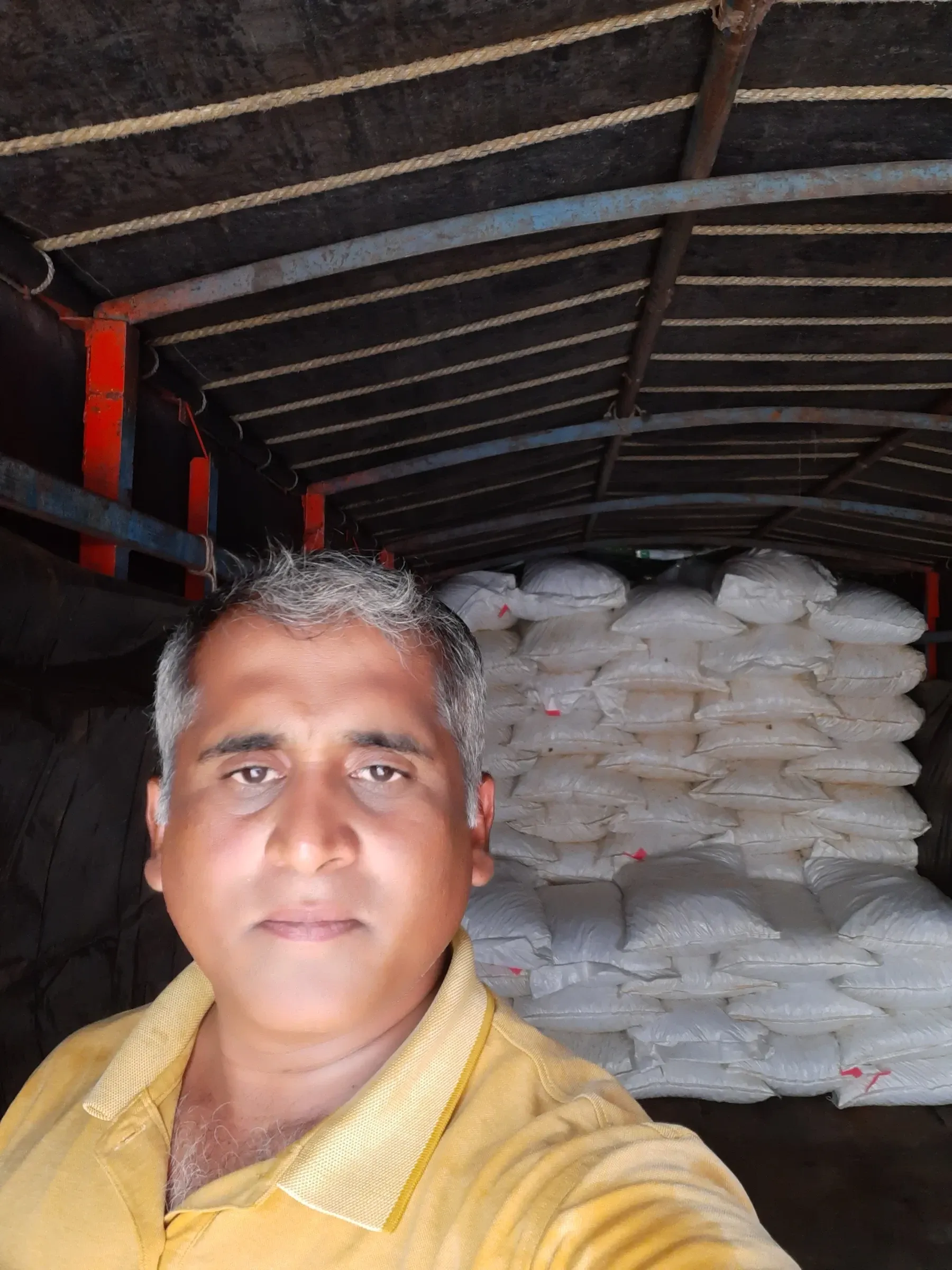 The procurement lead inside a truck loaded with sacks collected straight from the field