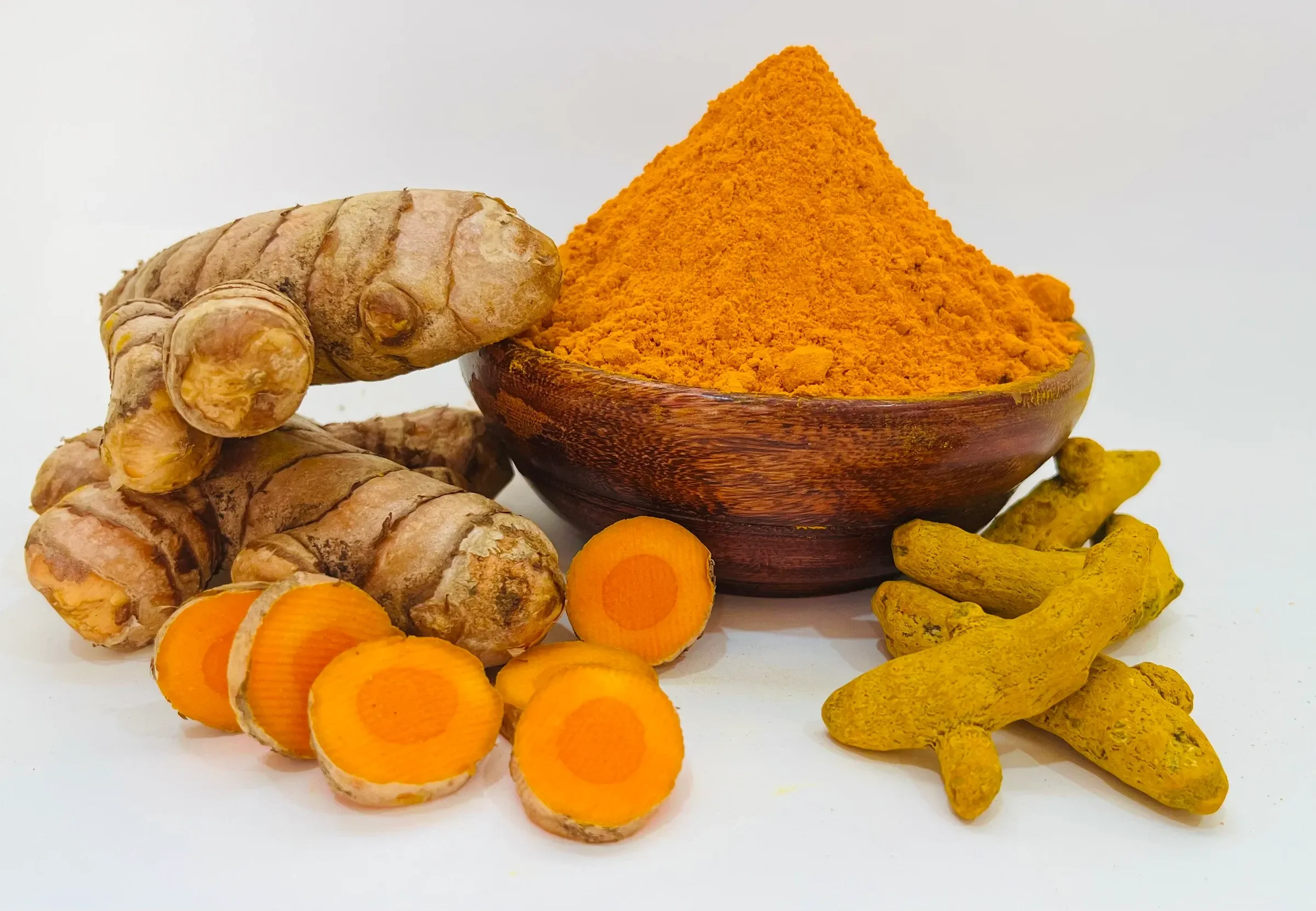 Fresh turmeric rhizome, cut slices, dried fingers and ground powder together on white